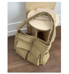 Detail of khaki multi-pocket tote bag with wide strap on a rustic wooden background