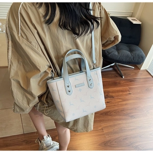 Détail du sac seau élégant avec imprimé cerf et anses bleues porté par un mannequin