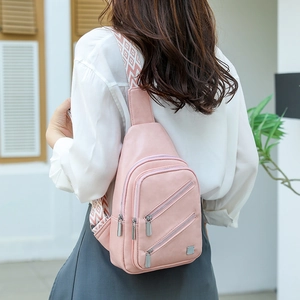 Close-up of pink crossbody bag with triple zipper detail and geometric jacquard strap