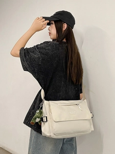 Cream canvas messenger bag with dinosaur pendant and adjustable strap for students
