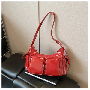 Detail of red patent leather shoulder bag with multiple zippered pockets and silver hardware