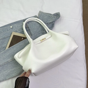 Detail of white lychee leather texture with gold metal clasp on a stylish tote bag