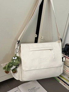 Minimalist cream canvas messenger bag with dinosaur plush charm and crossbody strap