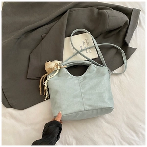 Detail of light blue crocodile pattern bucket bag with bear pendant and silk ribbon decor