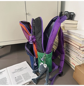 Detail of color-block multi-pocket backpack with frog pendant and durable zippers