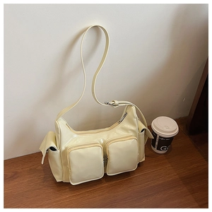 Detail of cream glossy patent leather shoulder bag featuring multi-pocket functional design