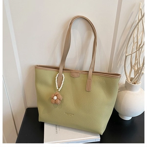 Détail du sac cabas vert clair avec texture litchi et pendentif fleur en perles