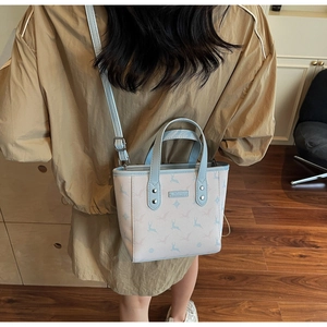 Vue détaillée du sac seau beige et bleu montrant la plaque logo et le motif animalier