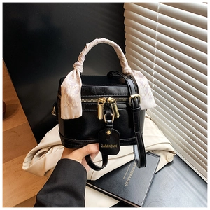 Détail du sac boîte noir avec poignée en foulard de soie sur vêtements beiges