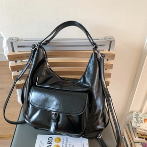 Detail der glänzenden schwarzen Kunstledertasche mit Metallschnalle und Reißverschluss