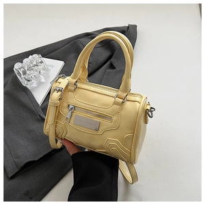 Detalle de mini bolso Boston amarillo con cremallera metálica y placa con el logotipo