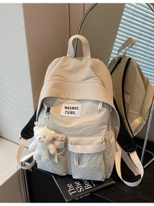 Zaino in tela beige da donna con doppie tasche frontali e ciondolo a forma di orsetto