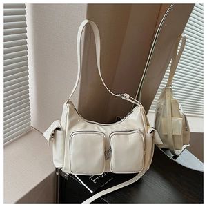 Detail of white glossy patent leather Y2K shoulder bag with multiple functional zippers
