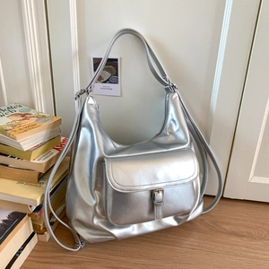 Detailansicht der silbernen Hobo-Tasche mit Metallic-Finish und Schnallentasche auf Holz