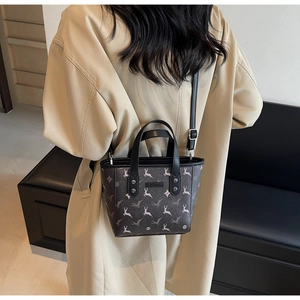 Vue détaillée du sac seau en cuir marron foncé avec un motif de cerf bondissant texturé
