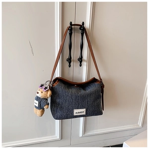 Close-up of blue denim bucket bag with brown leather trim and cute bear pendant charm
