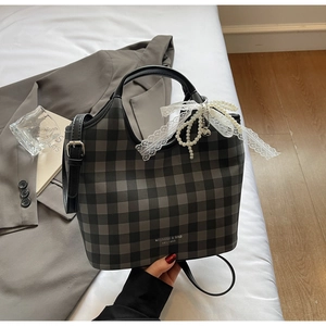 Close-up of a plaid tote bag with pearl pendant and lace ribbon on a white background