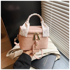 Détail du sac boîte rose avec poignée en foulard, zips dorés et étiquette en cuir