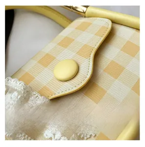 Detail of yellow checkered small bag with lace embroidery and leather-textured button