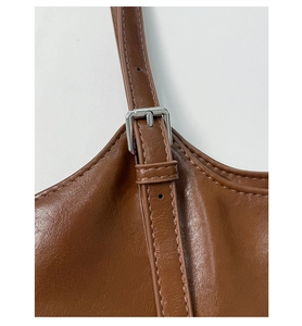 Close-up of adjustable brown leather shoulder strap with silver buckle and fine stitching