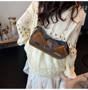 Detail of denim patchwork baguette bag with brown leather trim and zipper pockets