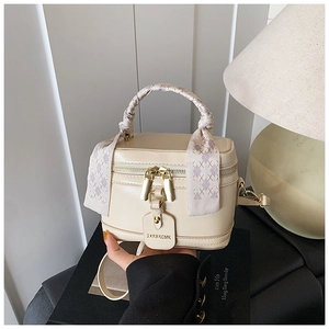Détail du sac boîte crème avec poignée en foulard de soie et étiquette de marque