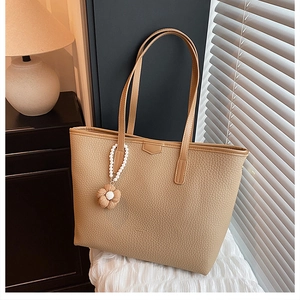 Détail du sac cabas en cuir litchi kaki avec son pendentif décoratif en perles et fleurs