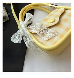 Macro view of checkered leather texture and white lace bow detail on hand bag