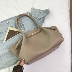 Detail view of taupe lychee leather tote bag with metallic turn-lock and decorative strap