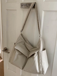 Minimalist beige large capacity nylon shoulder tote bag hanging on a white wooden door