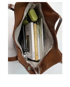 Spacious interior of a brown leather tote bag with a zipper pocket and daily essentials