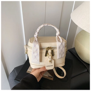 Détail du sac à main boîte en cuir crème avec anse en foulard et zips dorés