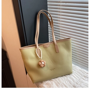 Détail du sac cabas vert clair à texture litchi avec logo doré et bijou de sac