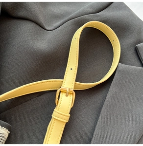 Detail of adjustable pale yellow faux leather shoulder strap with gold metal buckle clasp