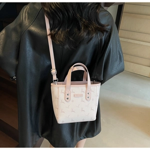 Détail d'un sac seau rose avec motif cerf porté à l'épaule par un mannequin