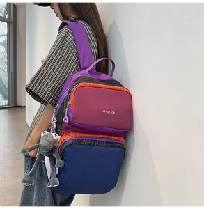 Close-up of multicolor backpack featuring secure zipper layers and a cute frog pendant charm