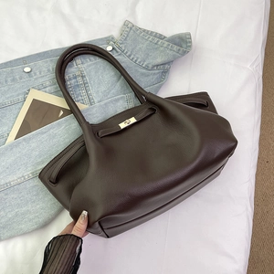 Detail of a vintage dark brown leather tote with a gold twist lock on denim
