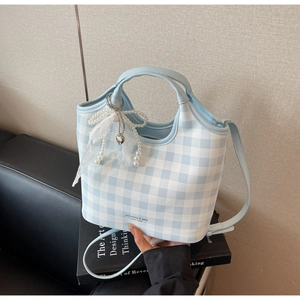 Detail of light blue gingham tote with pearl bow lace charm on design book