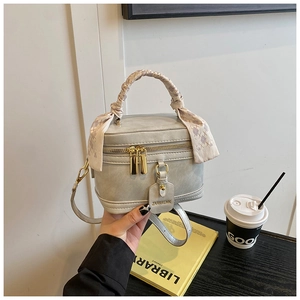 Détail du sac boîte gris avec zips dorés et poignée décorative en foulard de soie