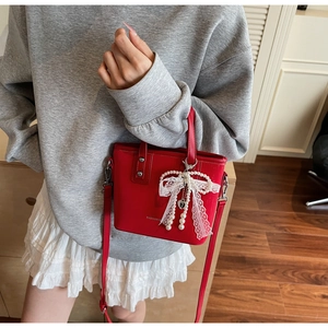 Detail of red leather bucket bag with a pearl lace bow and adjustable shoulder strap