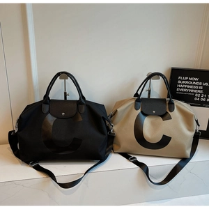 Detail of travel tote bags in black and khaki with leather flaps and C letter print