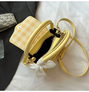 Detail view of yellow crossbody bag interior with checkered lining and lace bow