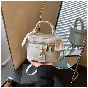 Close-up of elegant top handle box bag with silk scarf handle and golden hardware