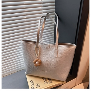 Détail du sac cabas en cuir argenté avec un élégant pendentif fleur en perles
