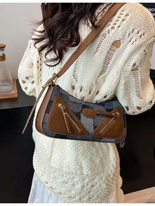 Vintage denim baguette bag with leather trim and zipper pockets shown on shoulder
