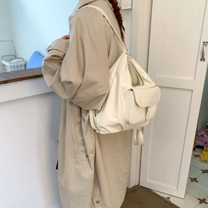 Seitenansicht des weißen minimalistischen Rucksacks kombiniert mit einem Khaki-Mantel