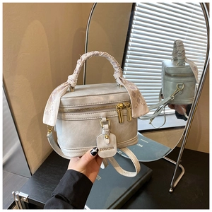 Détail d'un sac boîte gris avec poignée nouée, foulard en soie et détails dorés