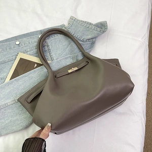 Detail of taupe litchi grain leather texture and metallic clasp on a stylish tote bag