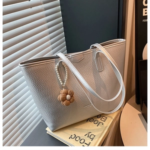Gros plan du sac fourre-tout gris clair avec texture grainée et breloque fleur perle