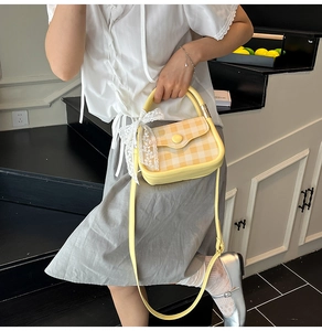 Detail of gingham mini square bag featuring a delicate white lace bow and yellow handle